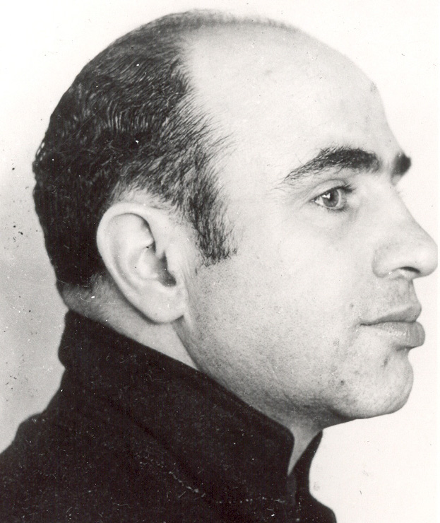 Mug shot of Al Capone in Alcatraz prison circa 1934: right-side profile, head and shoulders, in a dark high-collared jacket.