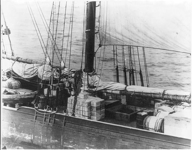 Sailing vessel with cases and barrels on its deck, seen from the cutter.
