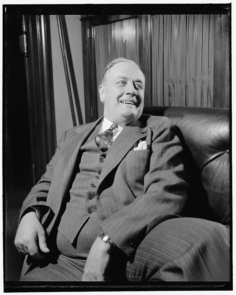 Senator Alexander Wiley seated on a leather couch, smiling and looking to one side.