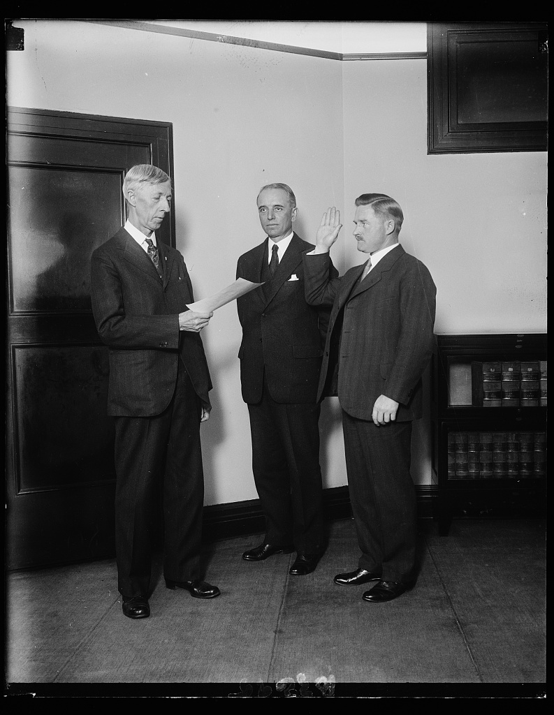 Three men at the swearing-in of G.A. Youngquist as Assistant Attorney General, with Attorney General William D. Mitchell.