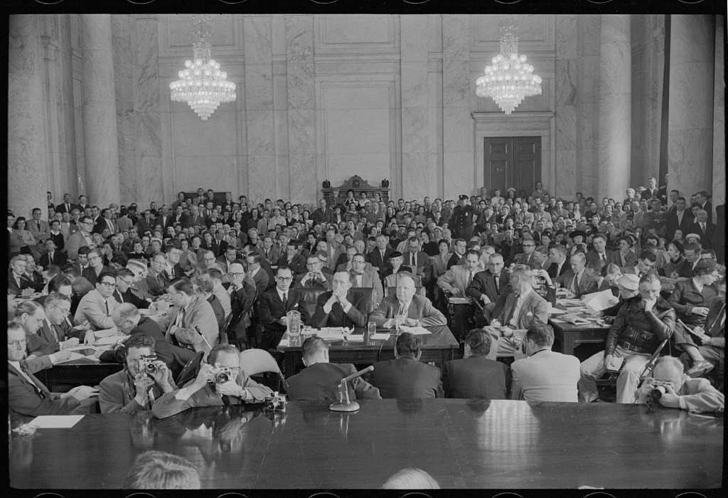Wide view of a crowded Senate hearing room with spectators and press before a long committee table.