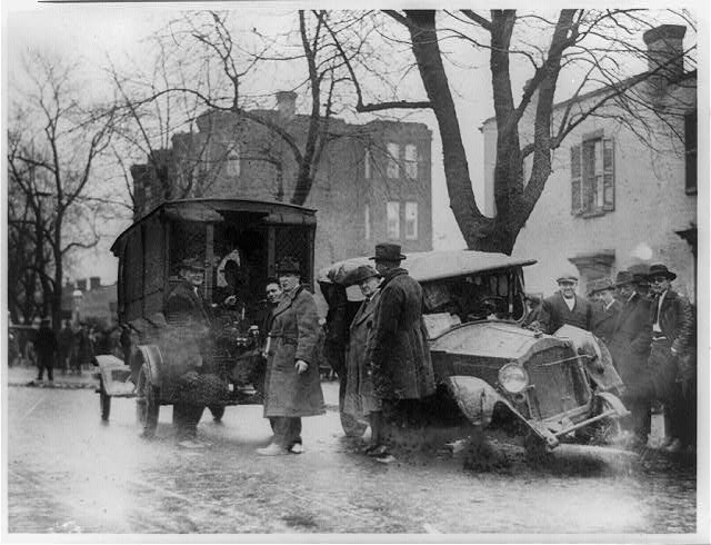 A wrecked automobile on a Washington street with bystanders gathered around it.