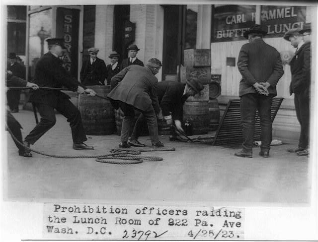 Men handling barrels on a Washington sidewalk in front of a storefront lunch room.