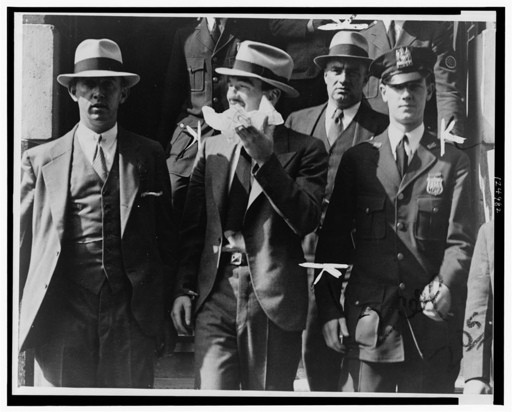 Vincent Coll leaving a courthouse surrounded by police officers.