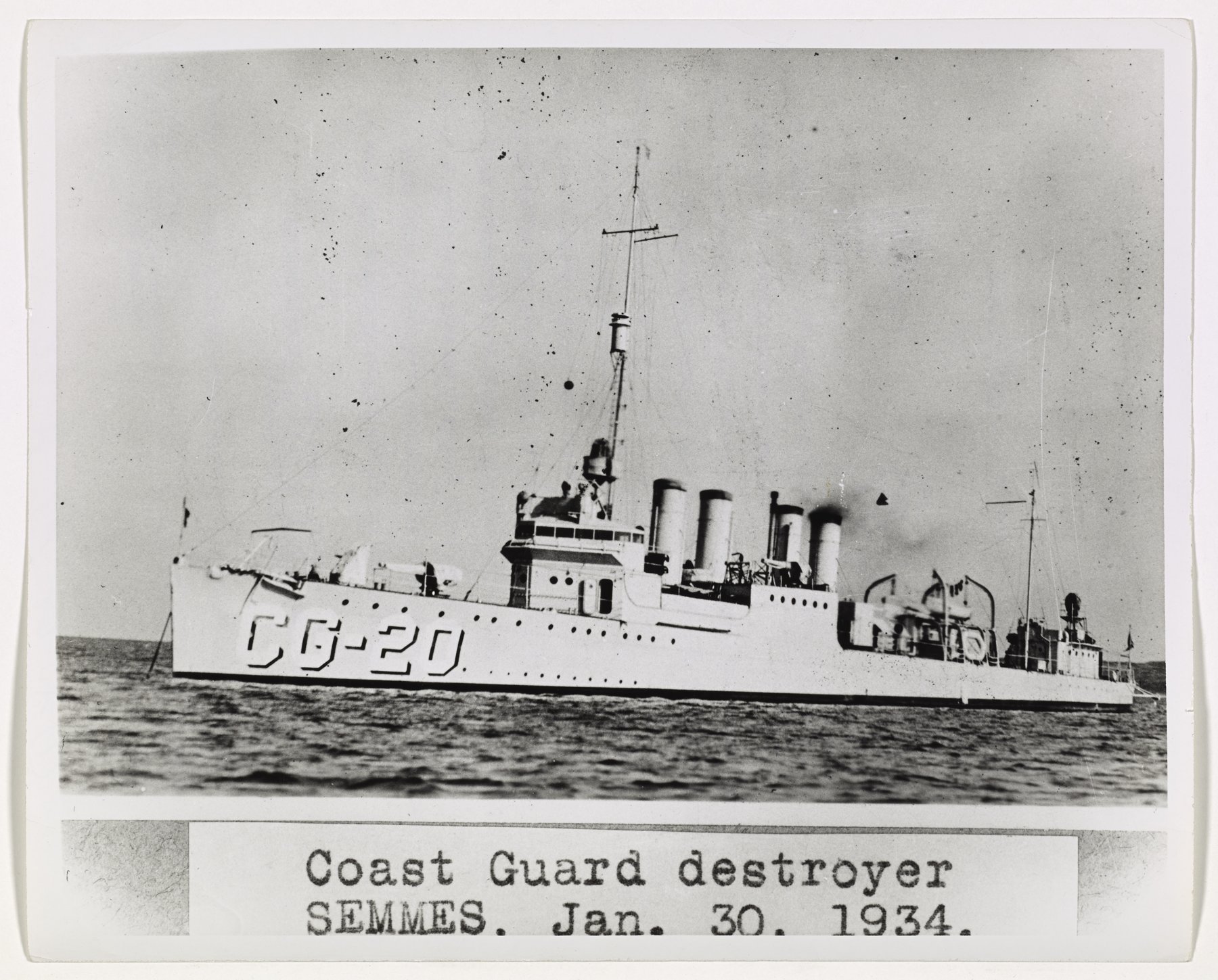 A four-stack destroyer with hull number CG-20 at sea, above a typed caption strip on the mount.