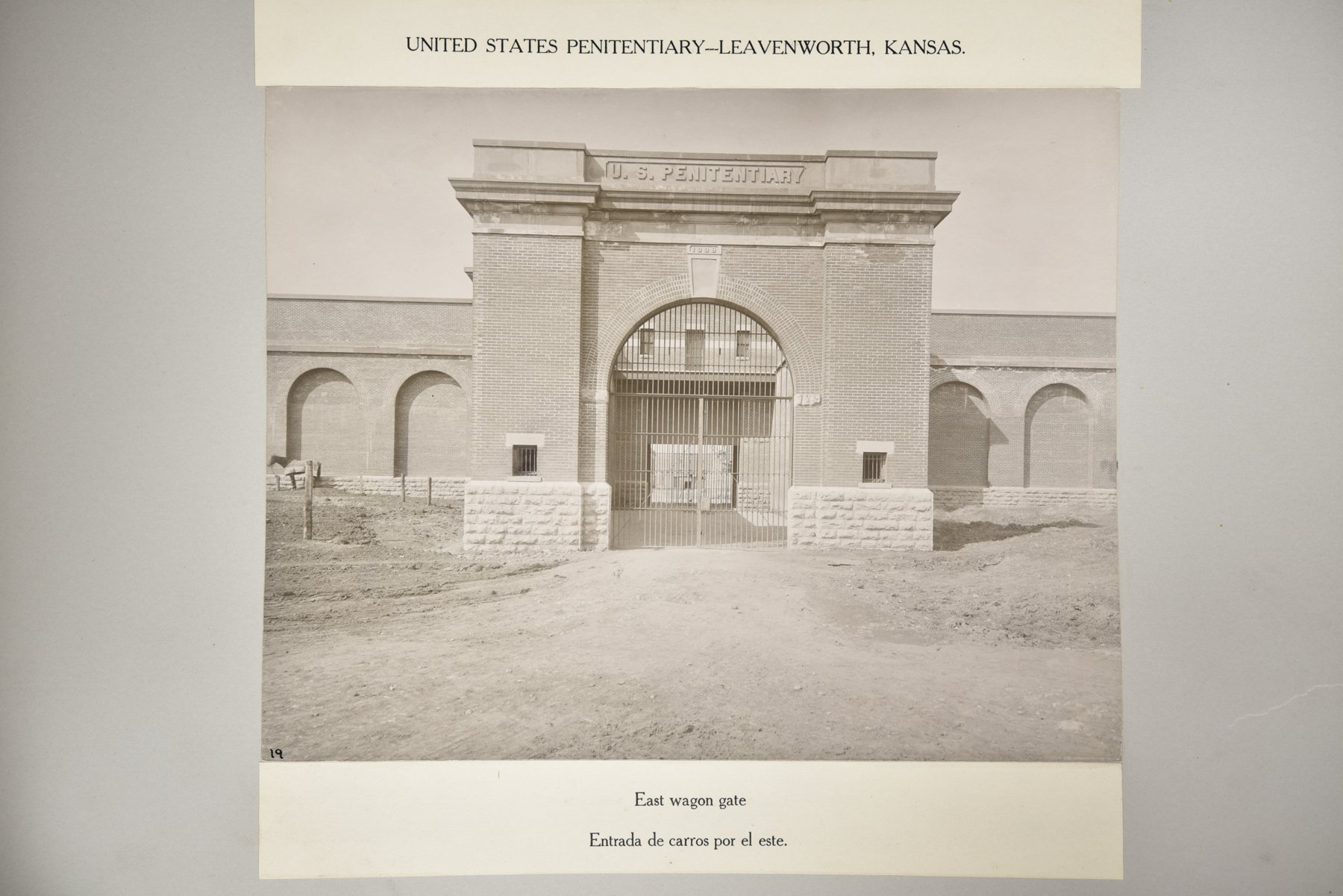 Album page headed United States Penitentiary, Leavenworth, Kansas, with a photograph of an arched brick gateway inscribed "U, above the caption East wagon gate.